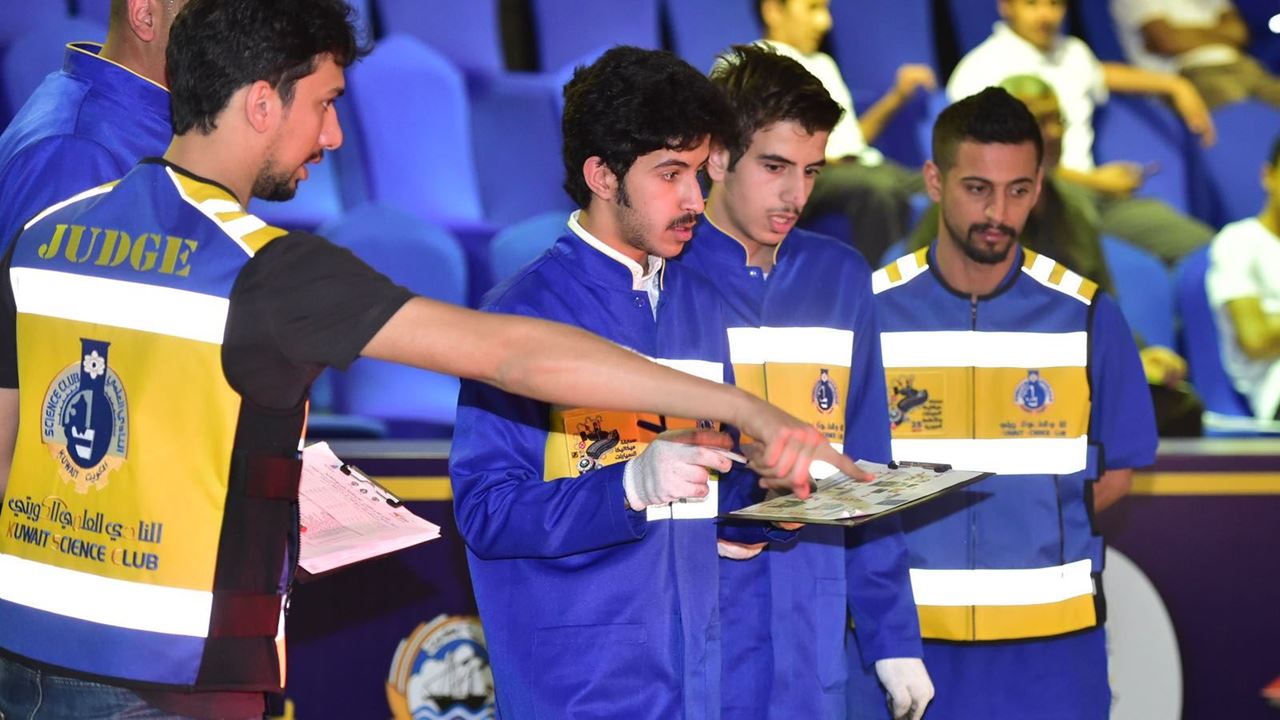 المحكم عبدالله القلاف مع مجموعة من الطلاب المشاركين في المسابقة
